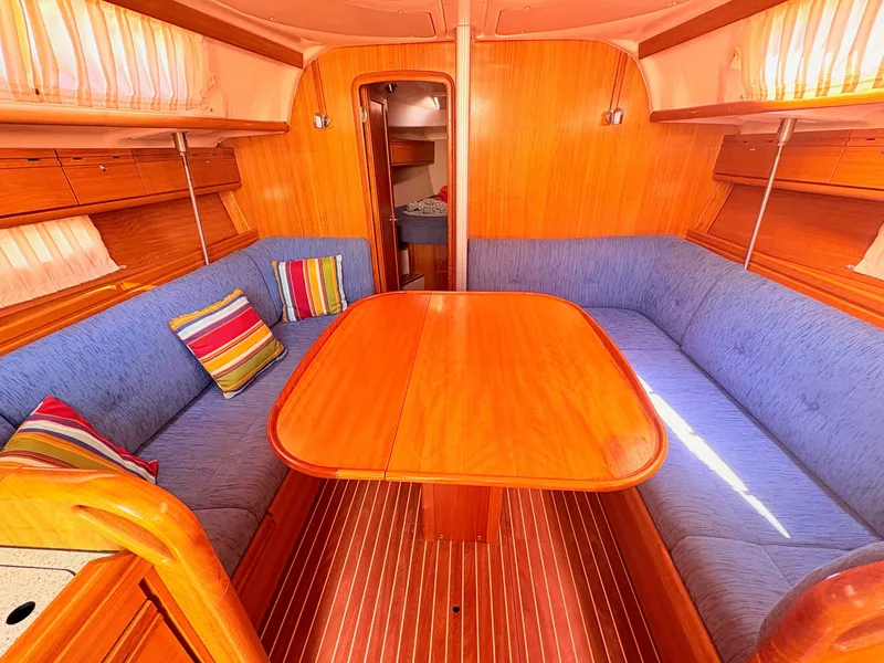 Slide: The Image of The interior of a 2008 Bavaria Cruiser 38 features a cozy seating area with blue cushions and colorful pillows. - 20