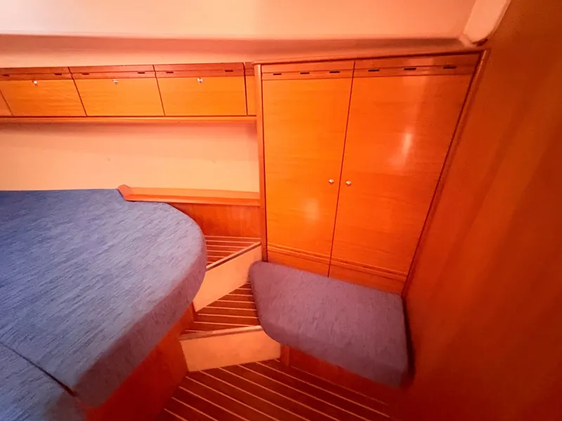 Slide: The Image of The interior cabin of a 2008 Bavaria Cruiser 38 features wooden cabinetry and blue upholstery. - 33