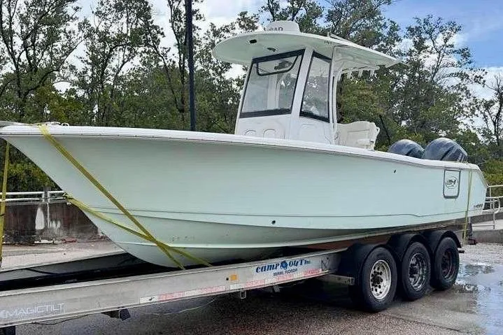 Slide: The Image of 2018 Sea Hunt Gamefish 25 boat on trailer, parked outdoors with trees in background. - 3