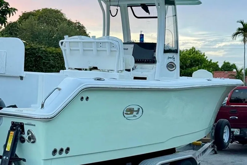Slide: The Image of 2018 Sea Hunt Gamefish 25 boat on trailer, parked outdoors with trees in background. - 2