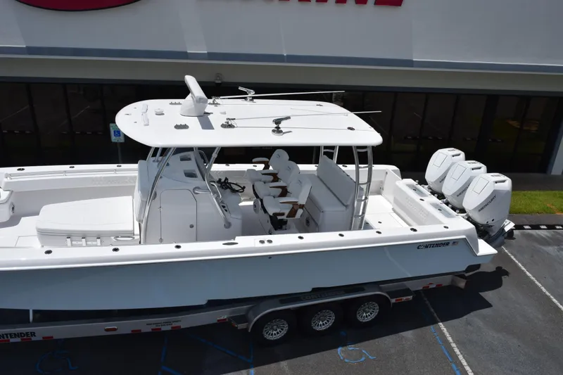 Slide: The Image of 2027 Contender 39 ST boat with triple engines on a trailer, parked outside a building. - 11