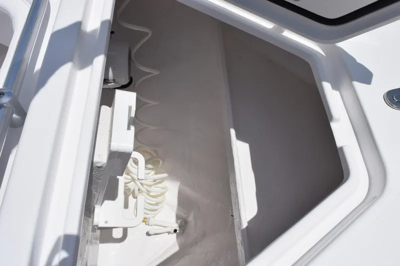 Slide: The Image of Open storage compartment on 2027 Contender 39 ST boat, featuring coiled hose and clean interior. - 40