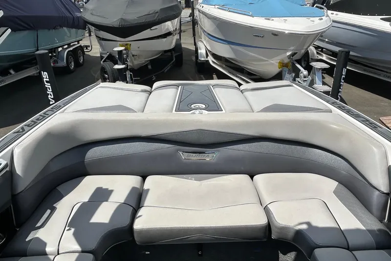 Slide: The Image of 2015 Supra SA 400 boat interior with cushioned seating, parked among other boats. - 7