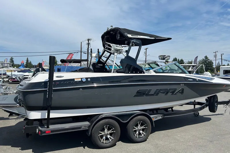 Slide: The Image of 2015 Supra SA 400 boat on trailer, sleek design, parked outdoors under clear sky. - 2