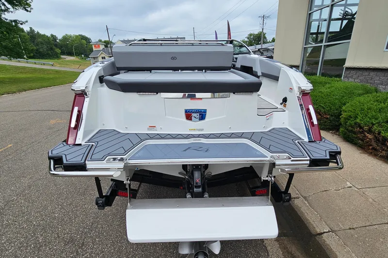 Slide: The Image of 2023 Cobalt R4 boat rear view with swim platform and seating, parked outdoors. - 6