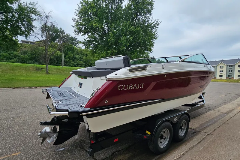 Slide: The Image of 2023 Cobalt R4 boat on trailer, parked on street with lush greenery background. - 3