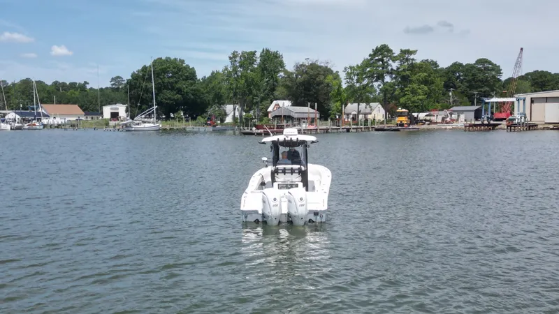 Slide: The Image of A 2024 Sea Hunt Gamefish 25 navigates calm waters, surrounded by trees and buildings. - 3