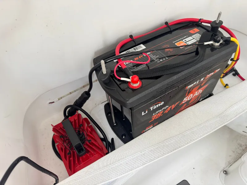 Slide: The Image of A boat battery setup with cables and a charger in a white compartment. - 22