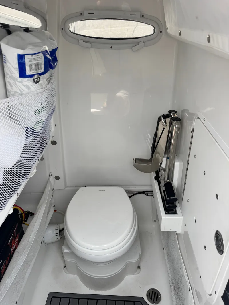 Slide: The Image of The image shows a compact boat toilet with white walls and a small window. - 17