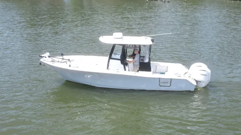 Slide: The Image of A white boat floating on calm water. It features a central helm and two outboard engines. - 1