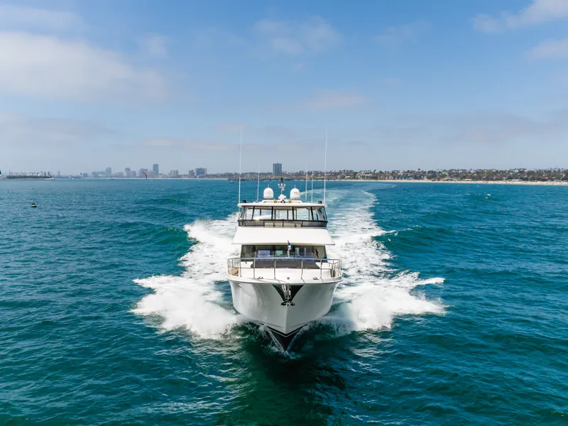Slide: The Image of A 2010 Ocean Alexander 68 Motor Yacht speeds across blue water, with a city skyline in the background. - 16