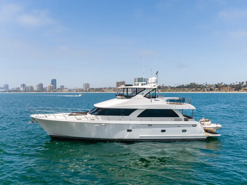 The Image of The 2010 Ocean Alexander 68 Motor Yacht glides elegantly on blue water with a city skyline in the background. - 0