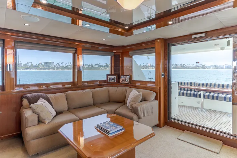Slide: The Image of The image shows the luxurious interior of a 2010 Ocean Alexander 68 Motor Yacht with a cozy sofa and wooden table. - 25