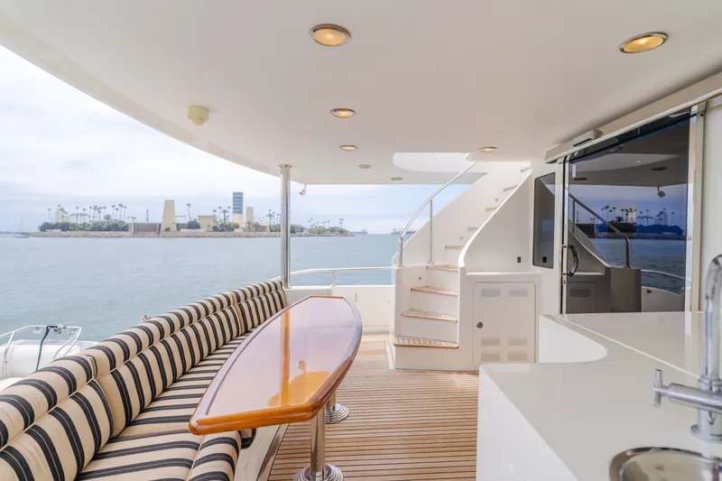 Slide: The Image of The 2010 Ocean Alexander 68 Motor Yacht features an elegant outdoor deck with striped seating and a wooden table. - 20