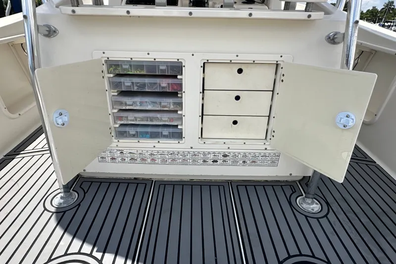 Slide: The Image of Open storage compartment on a 2004 Pursuit 3070 Center Console boat, featuring organized tackle boxes. - 6