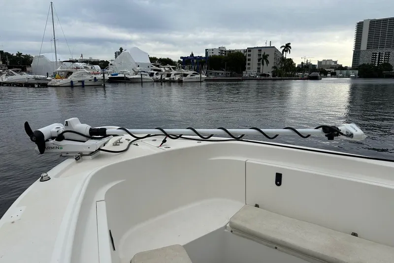 Slide: The Image of 2004 Pursuit 3070 Center Console boat docked, featuring a Garmin trolling motor, with marina backdrop. - 26