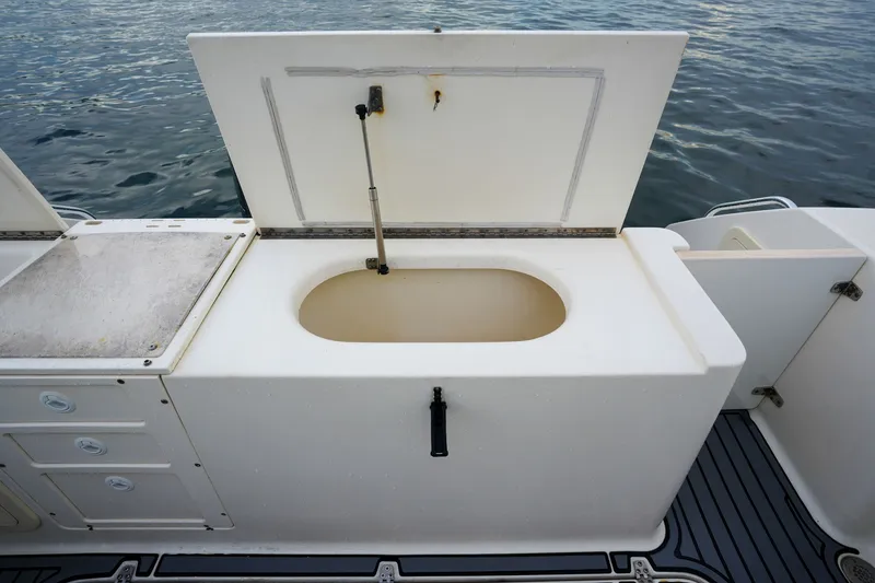 Slide: The Image of Open storage compartment on a 2004 Pursuit 3070 Center Console boat, near water. - 27