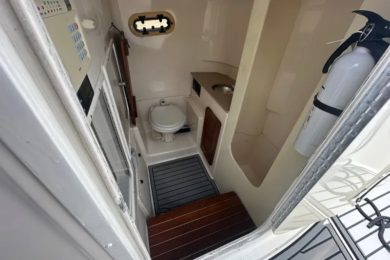 Slide: The Image of 2004 Pursuit 3070 Center Console boat interior with toilet, sink, and fire extinguisher. - 13