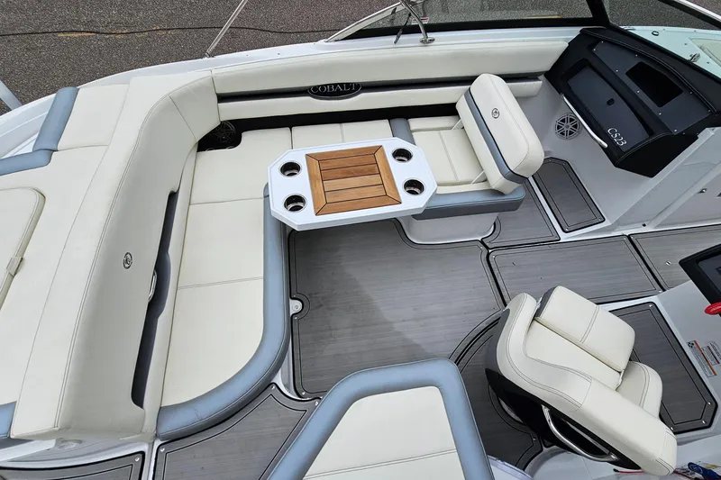 Slide: The Image of 2022 Cobalt CS23 boat interior with white seating and wooden table. - 9