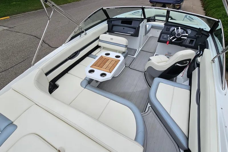 Slide: The Image of 2022 Cobalt CS23 boat interior with white seating, wooden table, and modern dashboard. - 8