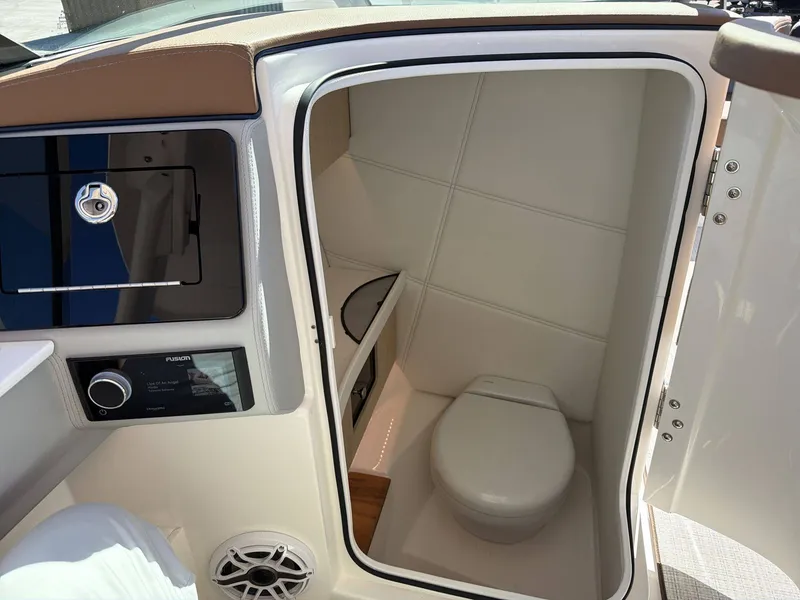Slide: The Image of The image shows a compact boat toilet with white walls and a small sink. - 12