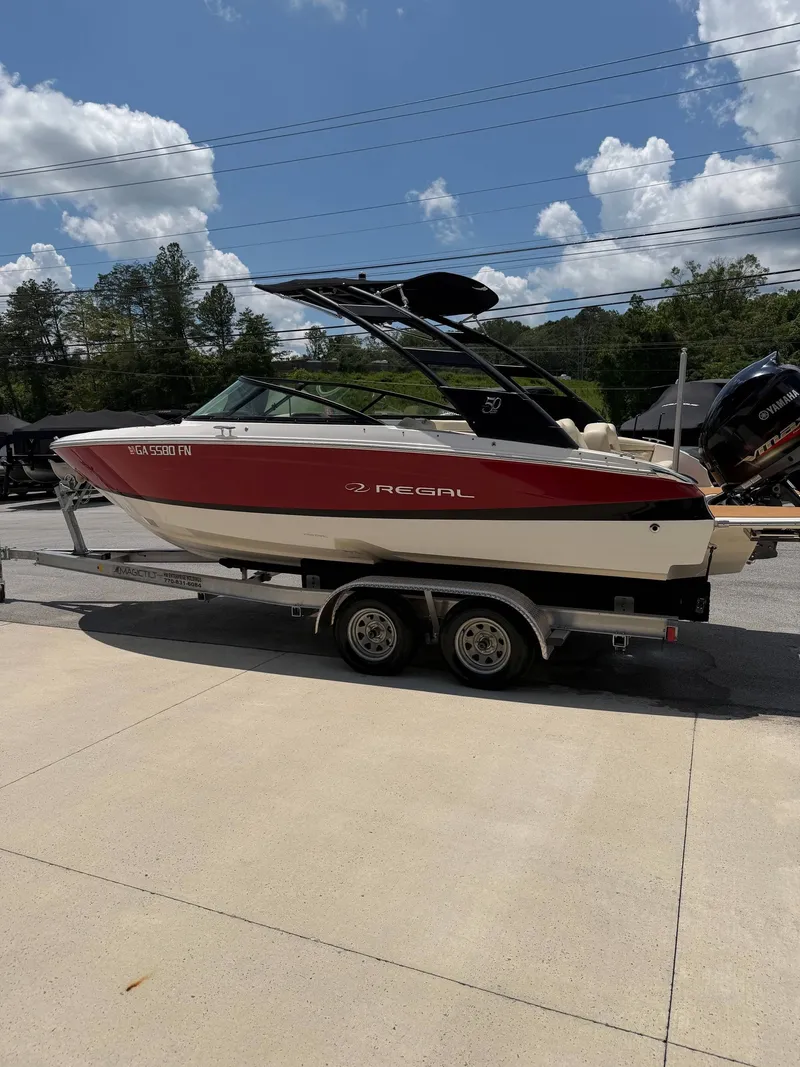 Slide: The Image of A 2021 Regal LX2 boat on a trailer. It features a red and white design. - 2