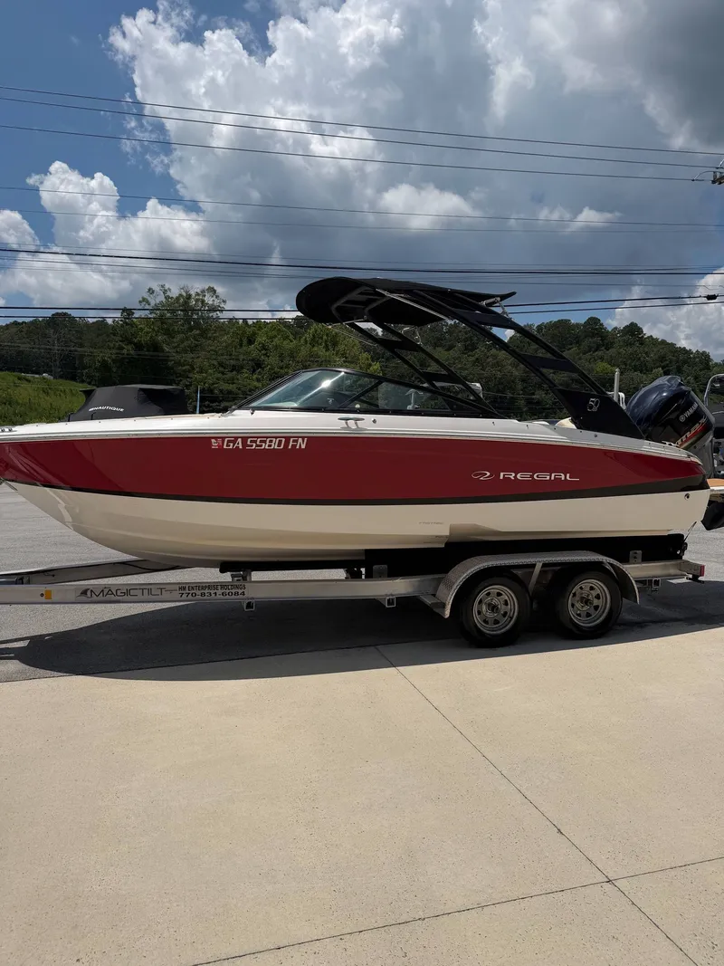 Slide: The Image of A red and white 2021 Regal LX2 boat on a trailer under a cloudy sky. - 3