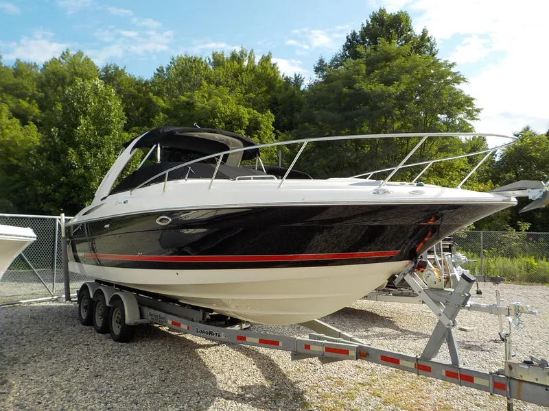The Image of A 2006 Monterey 298SC Super Sport boat on a trailer, surrounded by trees. - 1