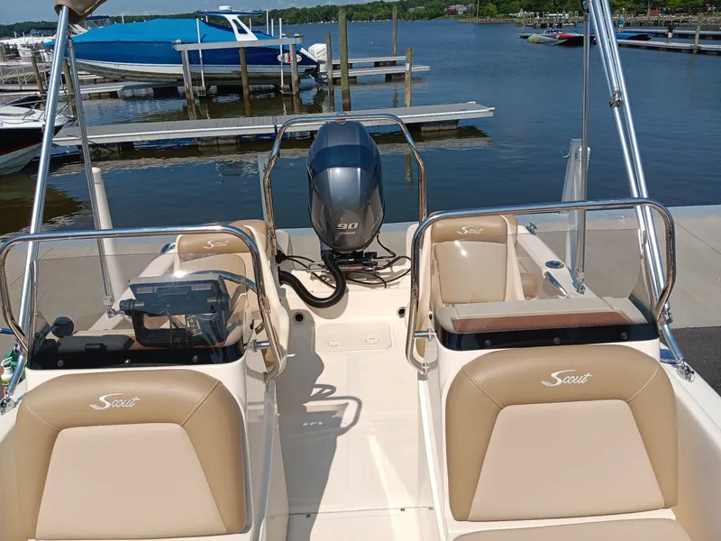 Slide: The Image of A 2020 Scout 175 Sport Dorado at the dock. It features beige seats and an outboard motor. - 2