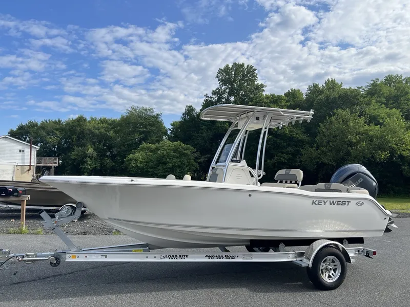 The Image of A 2027 Key West 203 FS boat on a trailer. It features a T-top and an outboard motor. - 1