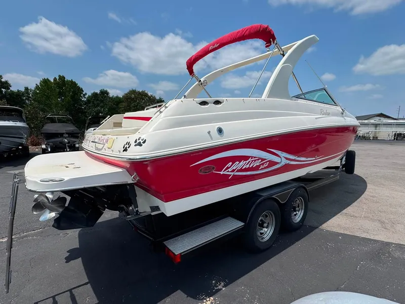 Slide: The Image of A 2006 Rinker 282 BR boat with a red and white hull, parked on a trailer. - 11