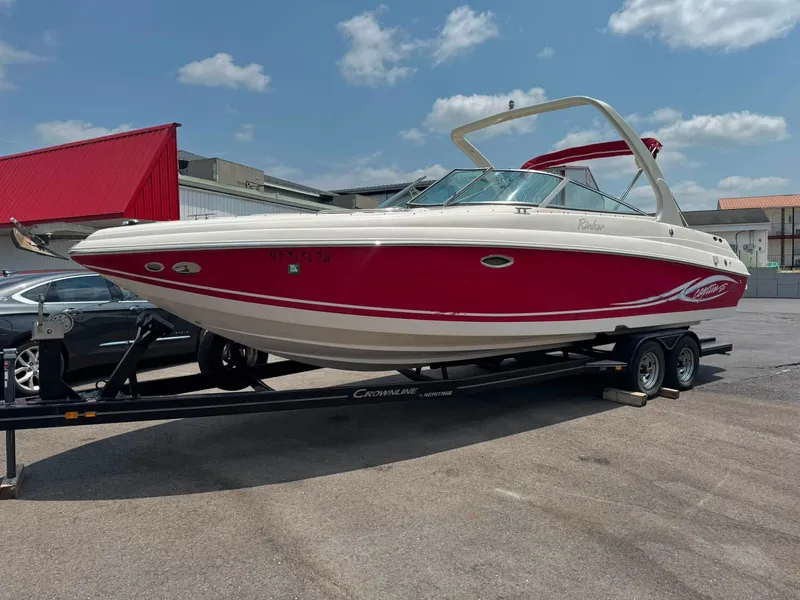 Slide: The Image of A red 2006 Rinker 282 BR boat on a trailer in a parking lot. - 14