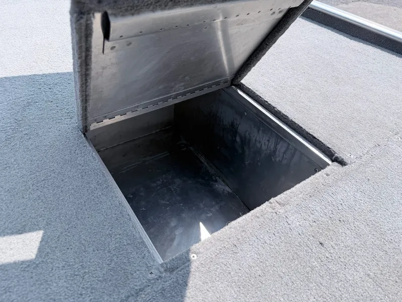 Slide: The Image of An open storage compartment on a boat with gray carpeted flooring. - 18