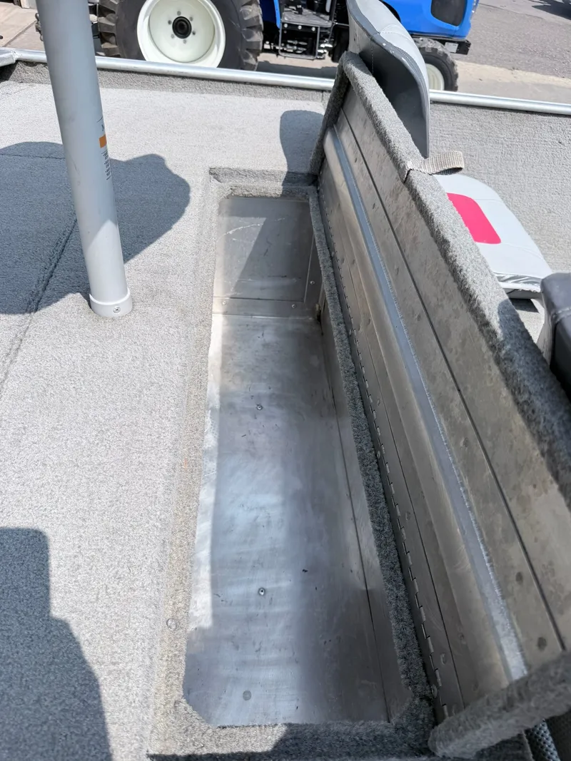 Slide: The Image of An open storage compartment on a 2011 Tracker Pro 165 boat, lined with gray carpet. - 20