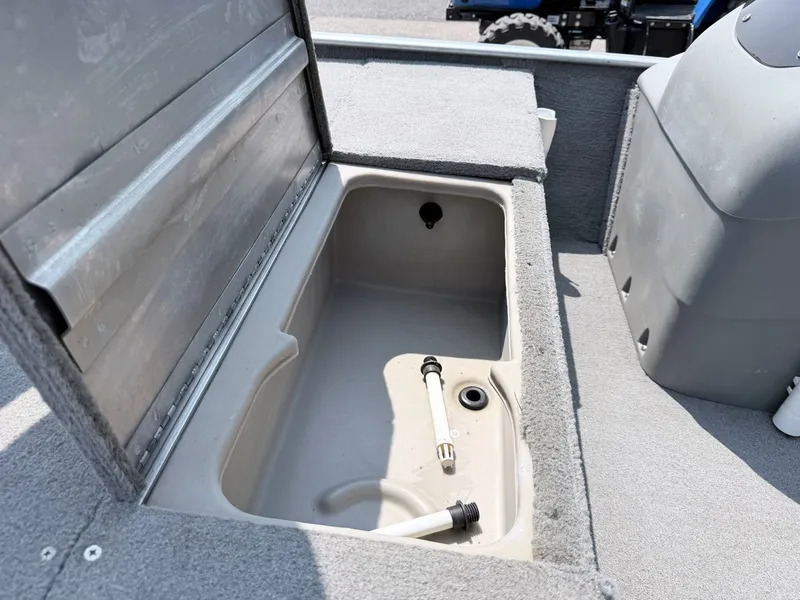 Slide: The Image of An open storage compartment on a 2011 Tracker Pro 165 boat, lined with gray carpet. - 12