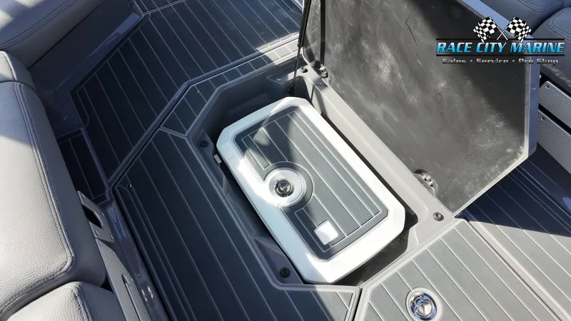 Slide: The Image of An open storage compartment on a boat with gray flooring and a white container. - 16