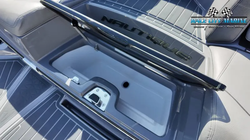 Slide: The Image of The image shows a storage compartment in the boat with a Nautique logo on the lid. - 38