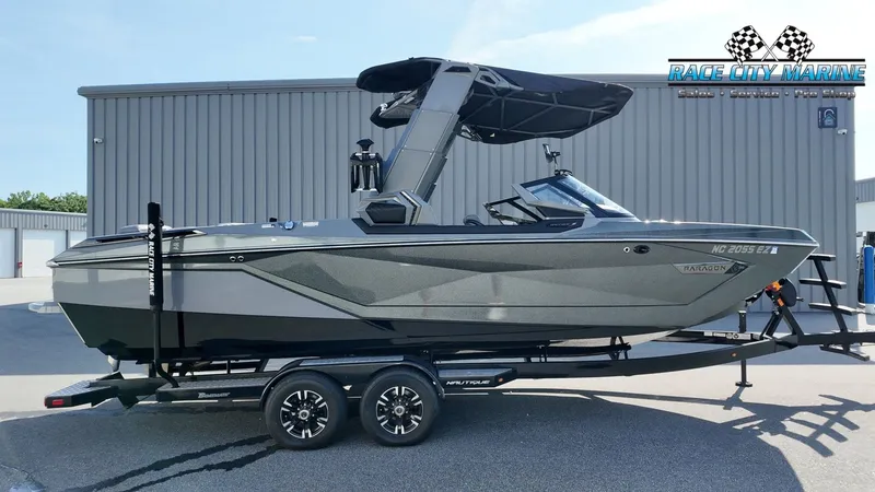 The Image of A gray 2022 Nautique Super Air Nautique G25 Paragon boat on a trailer in front of a building. - 1