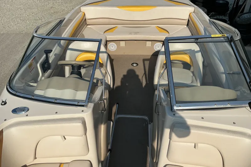 Slide: The Image of 2003 Glastron GX 225 boat interior with beige and yellow seating, open windshield, and steering wheel. - 14