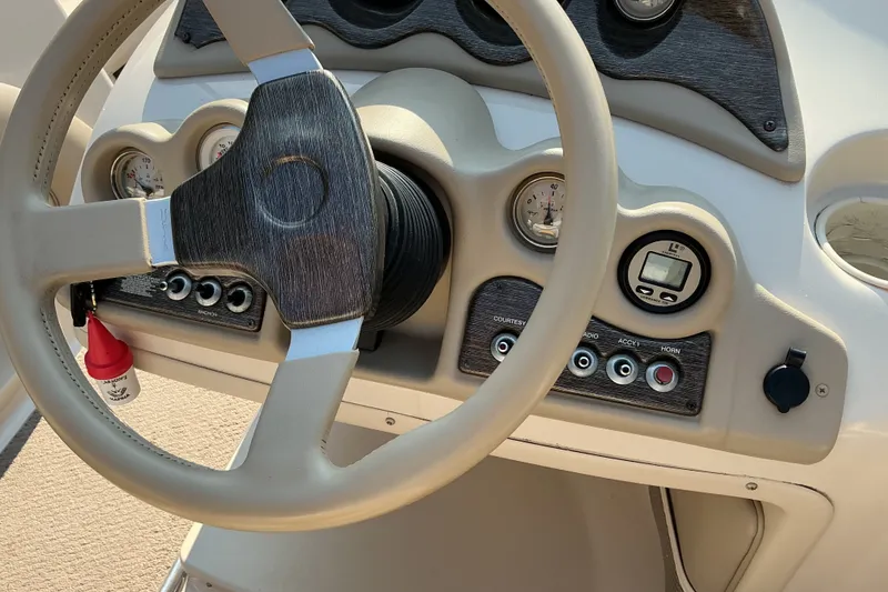 Slide: The Image of 2003 Glastron GX 225 boat dashboard with steering wheel and control panel. - 12