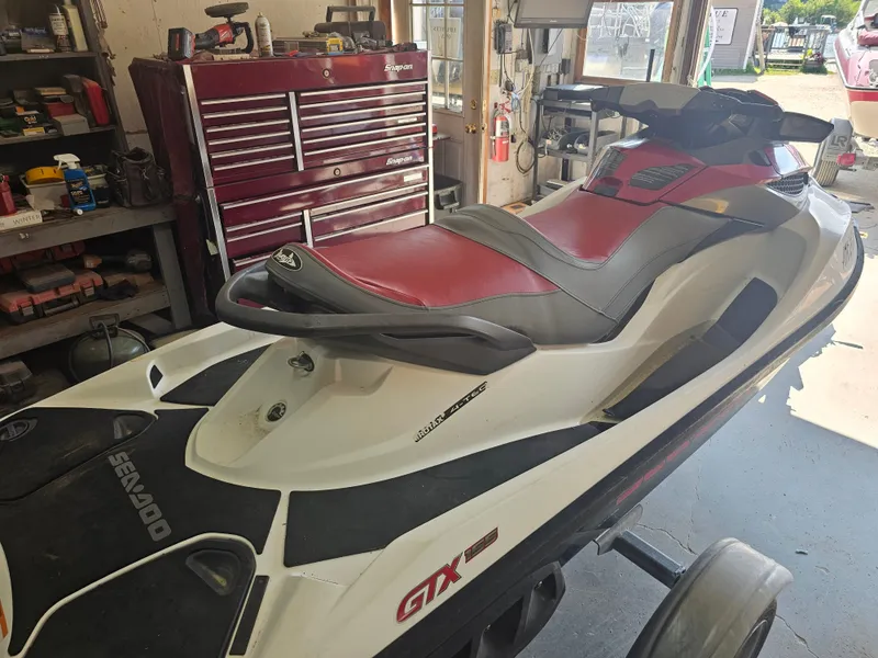 Slide: The Image of 2010 Sea-Doo GTX 155 jet ski in a workshop with a red seat and tools in the background. - 2