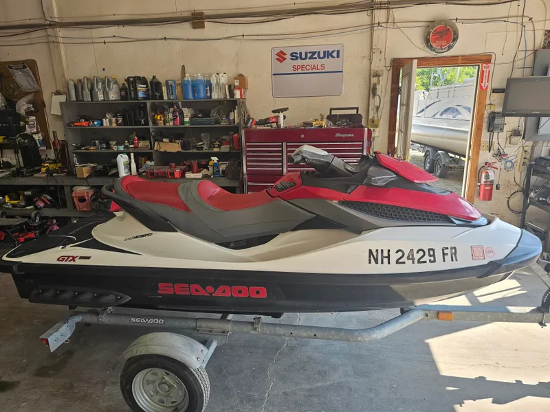 The Image of A 2010 Sea-Doo GTX 155 jet ski is on a trailer in a workshop. - 1