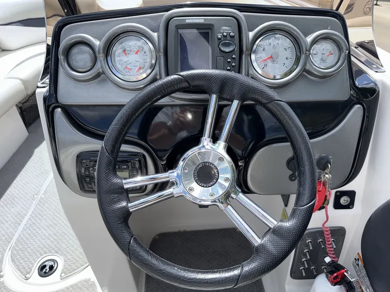 Slide: The Image of The image shows the helm of a 2015 Starcraft 211 SCX with a leather steering wheel and gauges. - 22