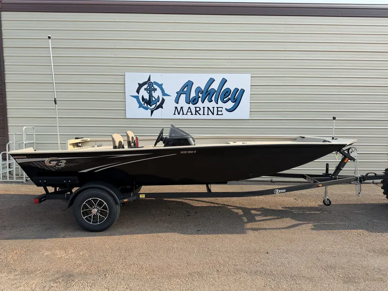 The Image of A black G3 Gator Tough 18SC-90 SHO boat on a trailer in front of a building with "Ashley Marine" sign. - 1