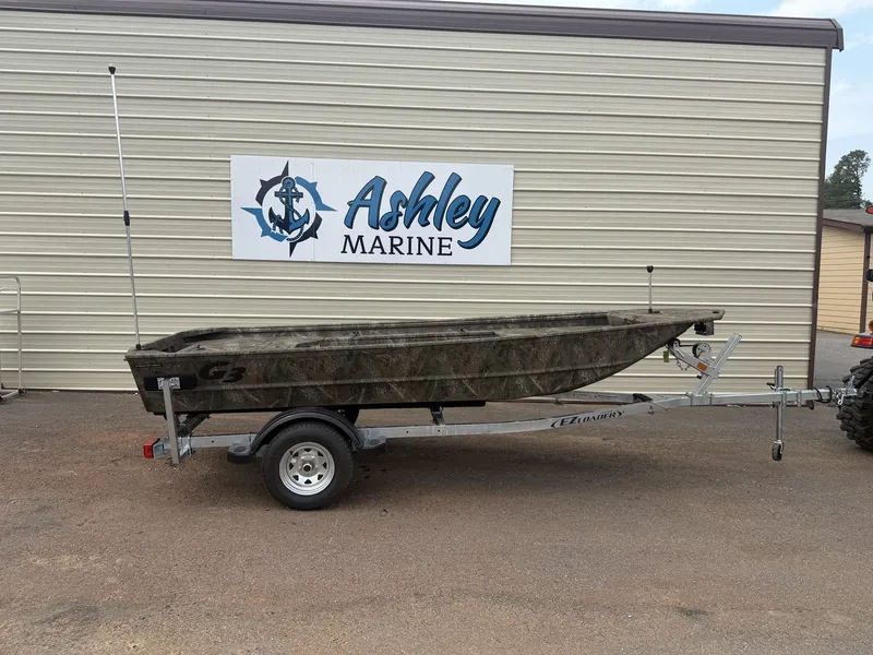The Image of A G3 Gator Tough 15DK-25HP boat on a trailer in front of a building with "Ashley Marine" sign. - 1