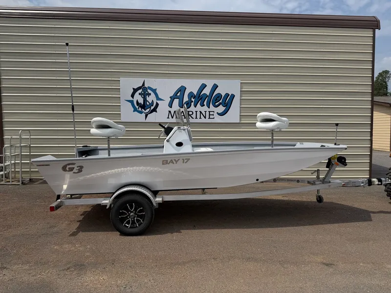 The Image of A white G3 Bay 17 boat on a trailer in front of a building with "Ashley Marine" sign. - 1