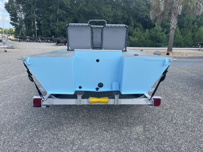 Slide: The Image of The image shows the rear of a light blue micro skiff on a trailer, surrounded by trees. - 4