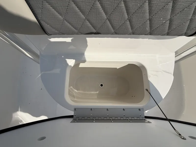 Slide: The Image of An open storage compartment on a 2027 Key West 203 FS boat, with a cushioned seat above. - 8