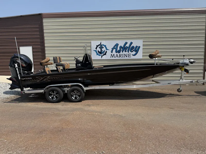The Image of A black Xpress Hyper-Lift Bay Series H24B boat on a trailer in front of a building. - 1