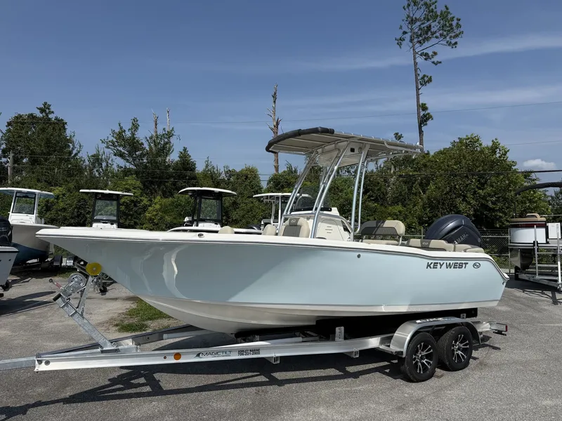The Image of A 2027 Key West 203 FS boat on a trailer, surrounded by trees and other boats. - 1